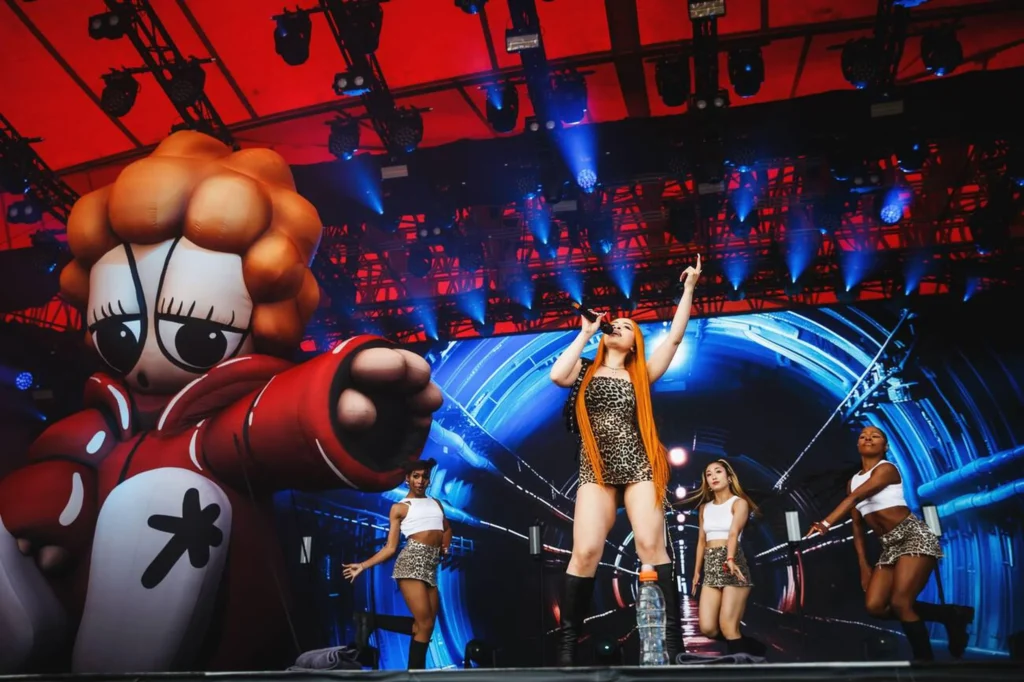 Ice Spice holding the microphone mid-performance, engaging with a cheering audience.