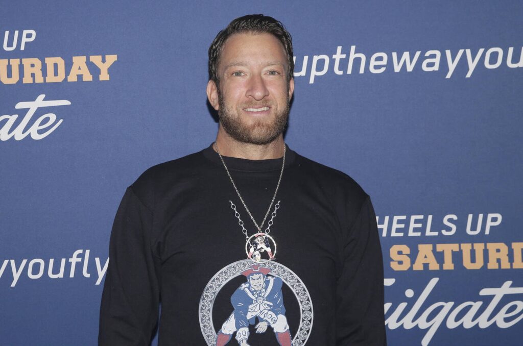 Dave Portnoy smiling confidently at a business event, representing his financial success. The image emphasizes 'Dave Portnoy Net Worth' and his $150 million media empire