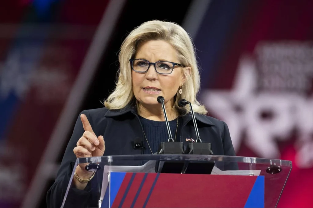 Liz Cheney speaking at a political rally, addressing supporters with determination.