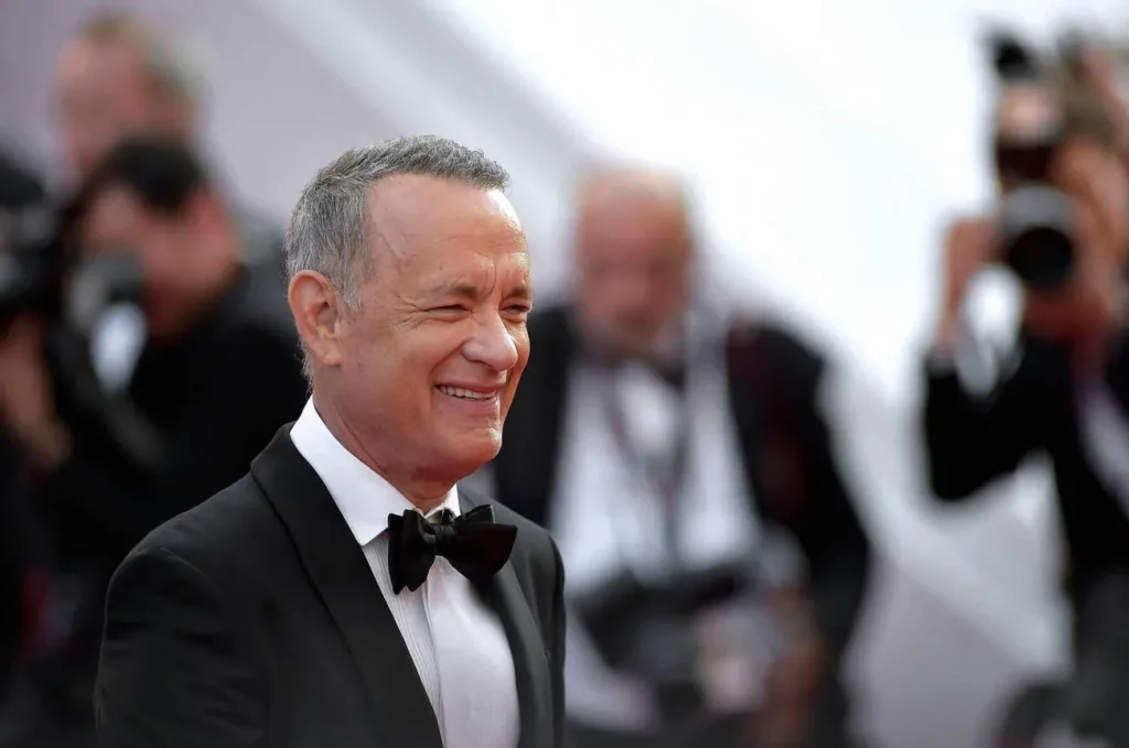 Tom Hanks at a film premiere, smiling and posing for photographers