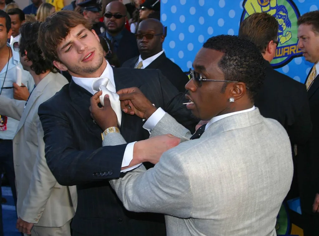 Ashton Kutcher and P. Diddy pose together at an event, both looking stylish.