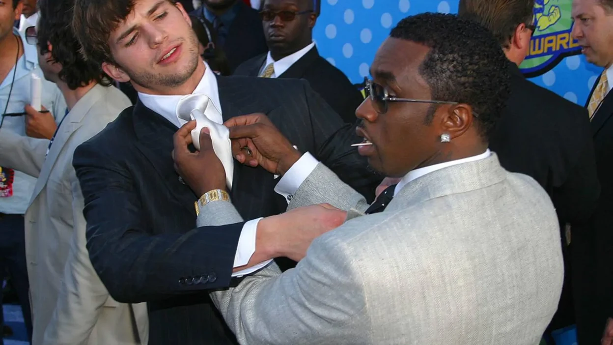 Ashton Kutcher and P. Diddy pose together at an event, both looking stylish.