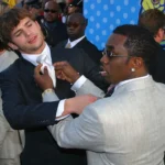 Ashton Kutcher and P. Diddy pose together at an event, both looking stylish.