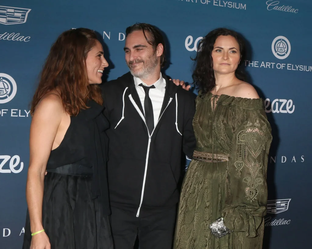 Joaquin Phoenix, Summer Phoenix, and Rain Phoenix posing together at the Art of Elysium 12th Annual HEAVEN Celebration, showcasing their close bond and artistic legacy