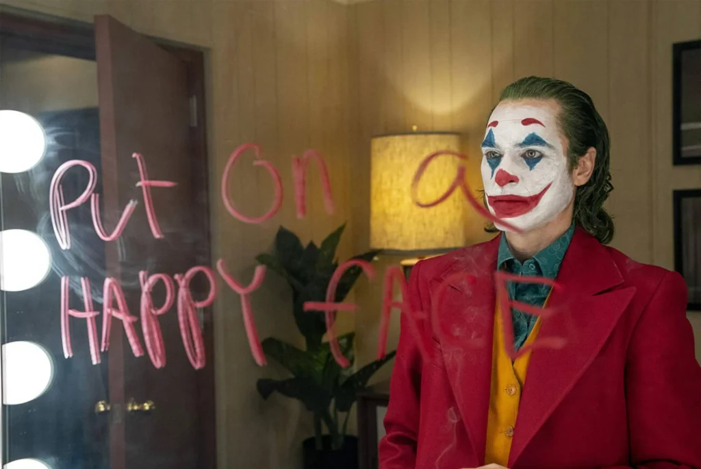 Joaquin Phoenix in character as the Joker, with smeared makeup and a chilling expression, embodying the psychological depth of the role.